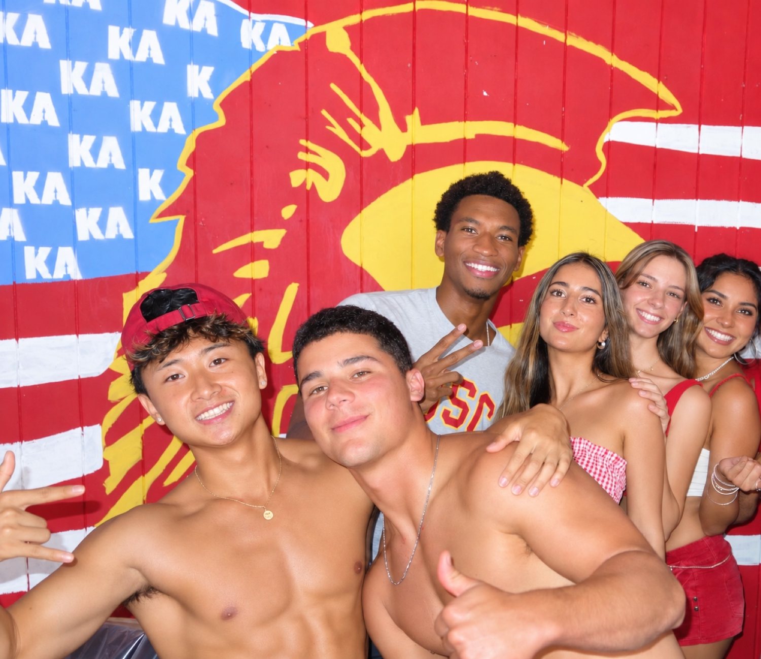Francis Ruan with friends in front of a painted Trojan mural