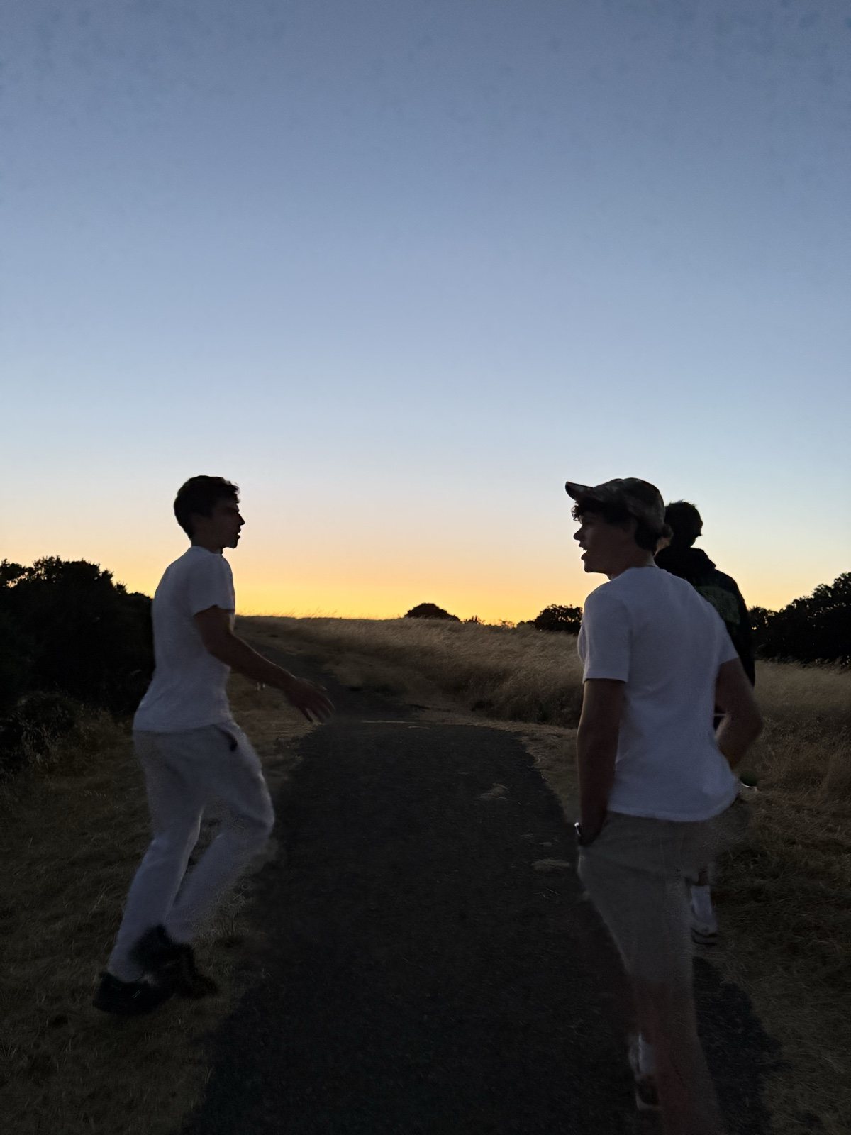 Two silhouettes on a trail at sunset